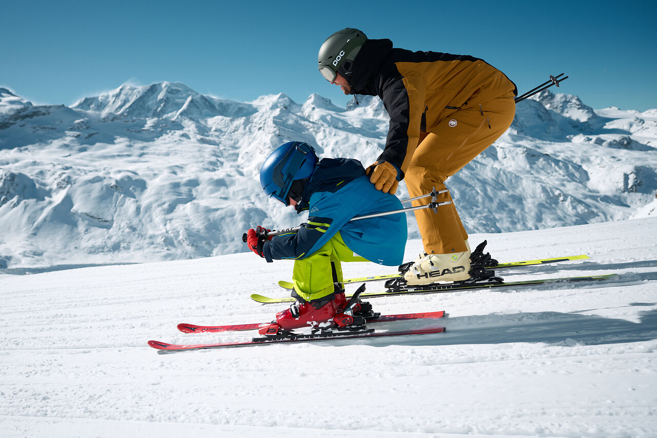 Kind macht seine ersten Versuche mit einem Skilehrer in Zermatt